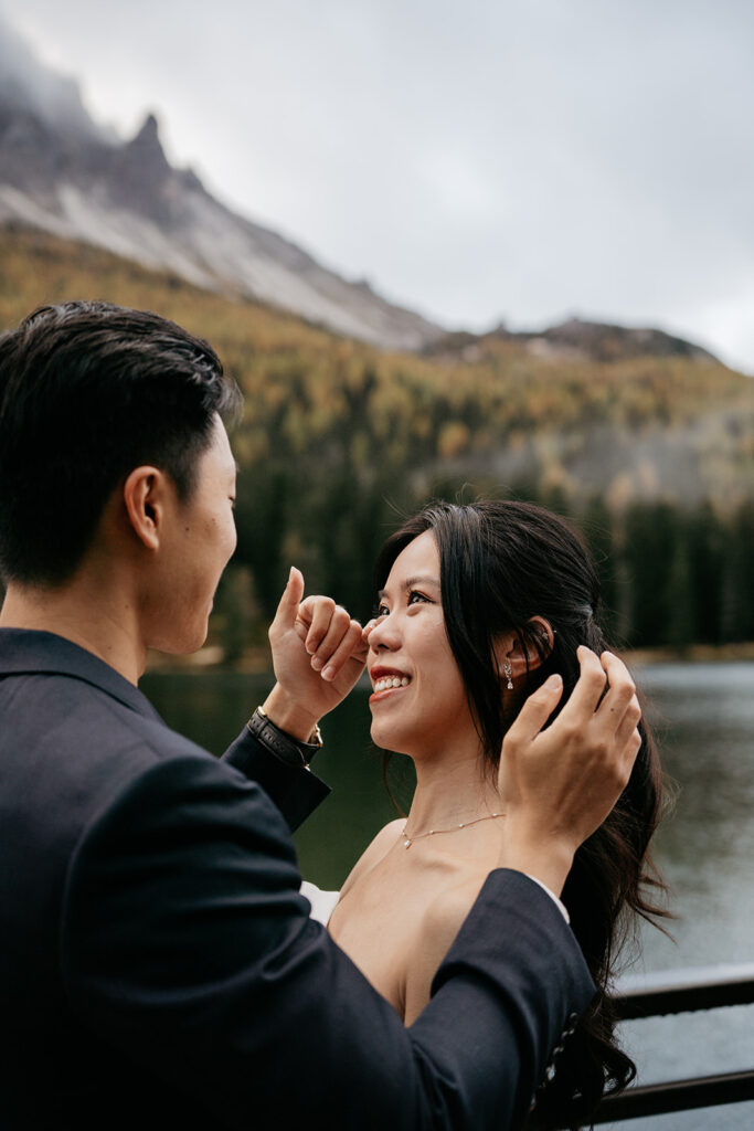 Couple smiling by a scenic mountain lake.