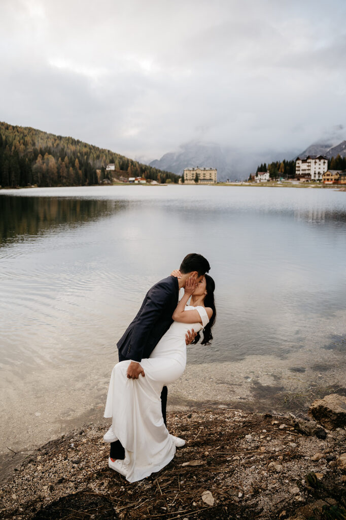 Couple kissing by serene lakeside scenery.