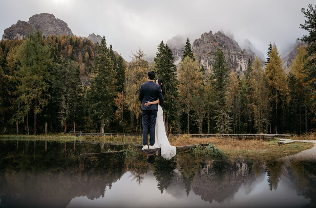 Couple by mountain lake surrounded by forest.