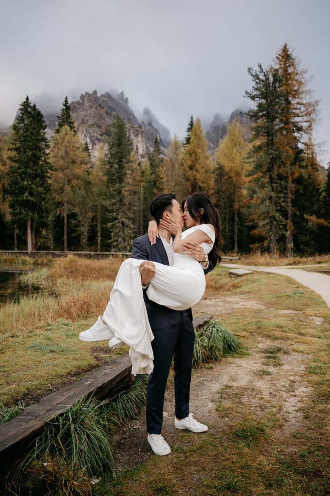 Couple kissing in forest, bride being carried.