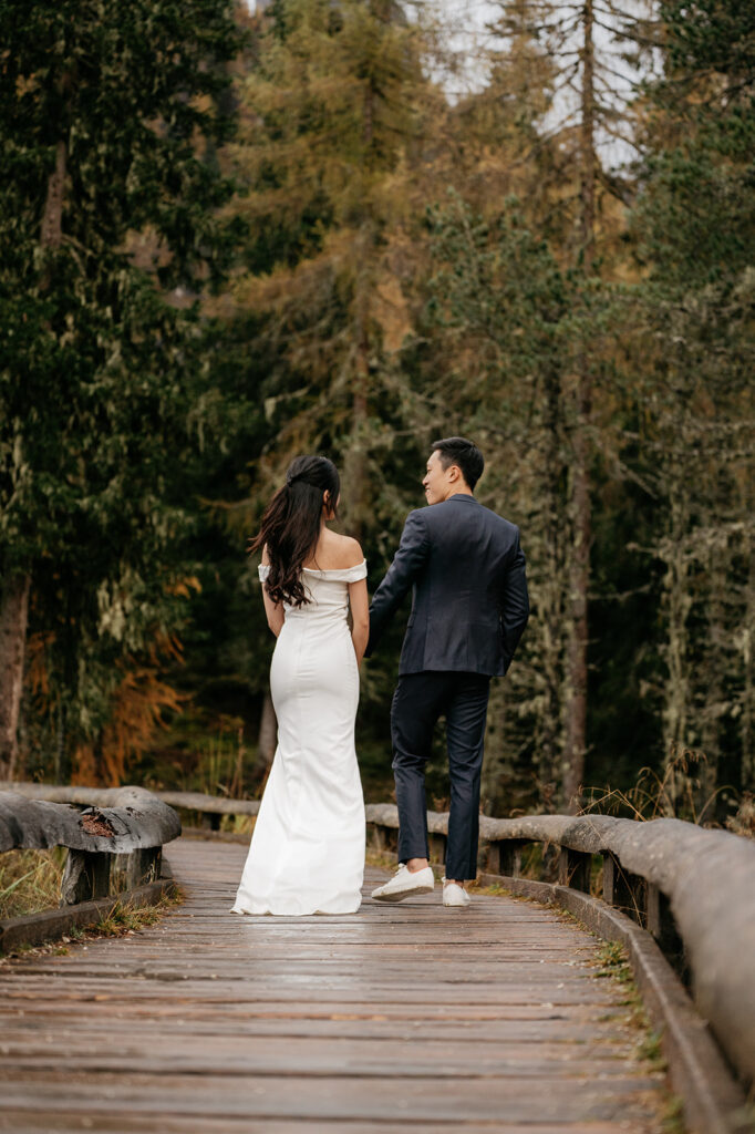 Couple walking on forest path in wedding attire.