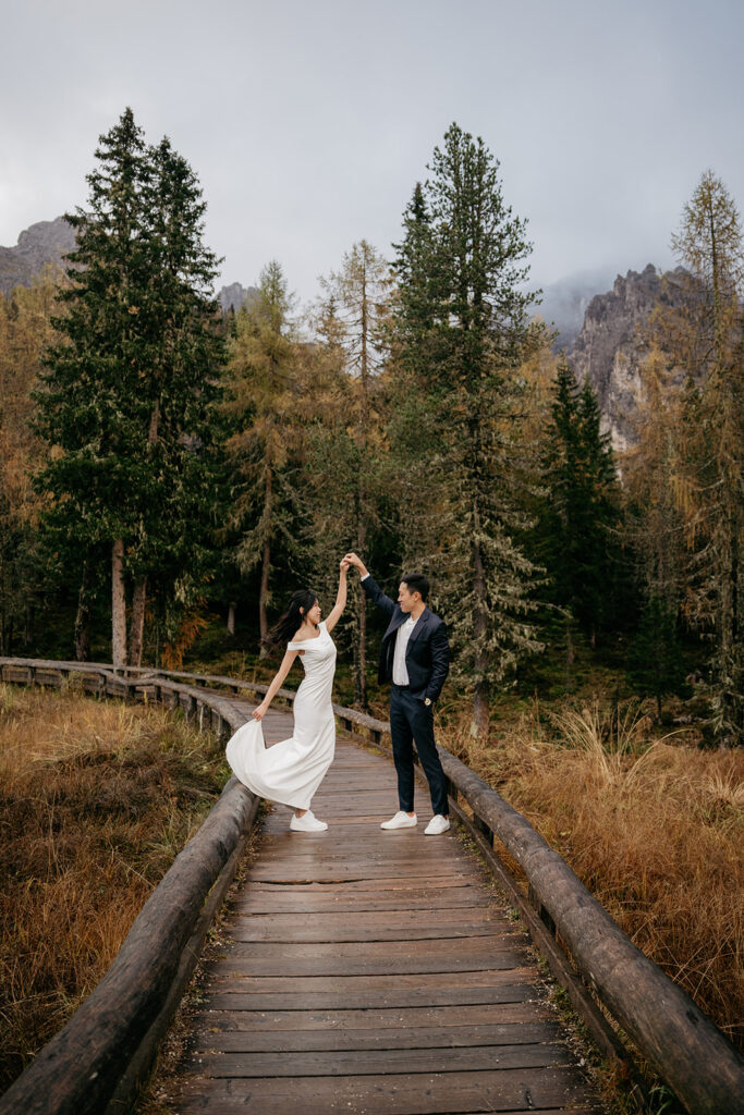 Couple dancing on wooden path in forest.