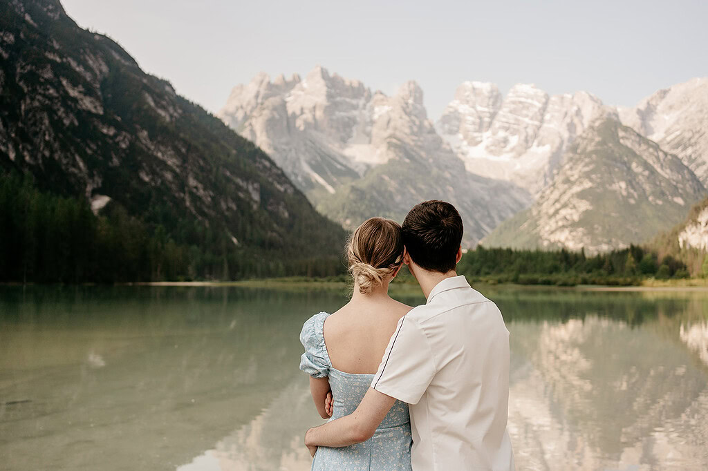 Couple embraces by mountain lakeside view.