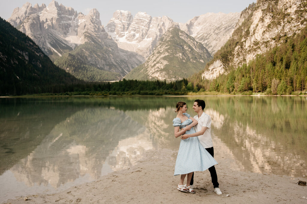 Couple embracing by mountain lake.