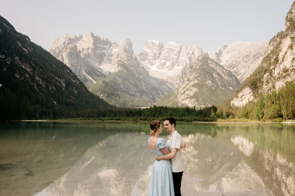 Couple embraces by scenic mountain lake view.