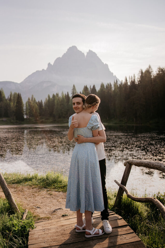 Couple embracing by lake with mountain backdrop