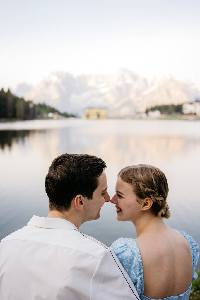 Couple smiling near a serene mountain lake.