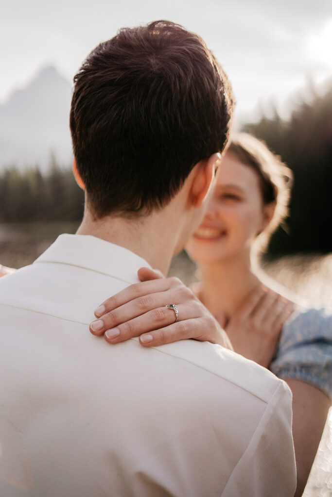 Close-up of couple embracing, engagement ring visible.