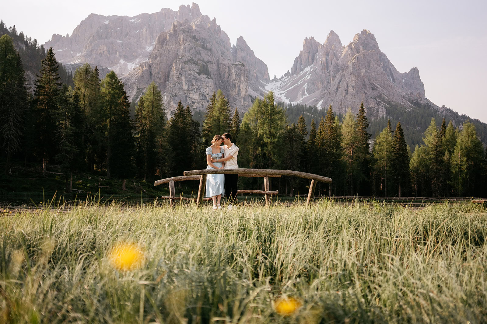 Couple embracing on bridge with mountain view.