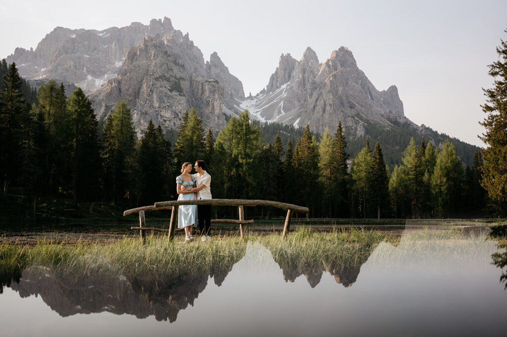 Couple standing by mountain lake, serene landscape view.