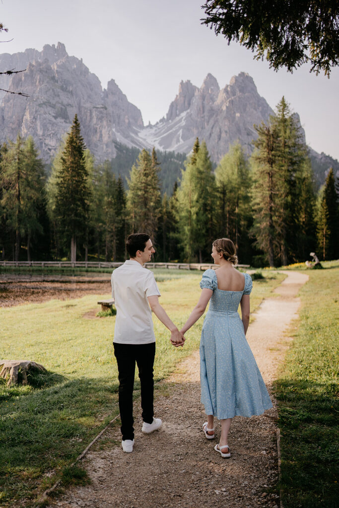 Couple walking on mountain path hand in hand.