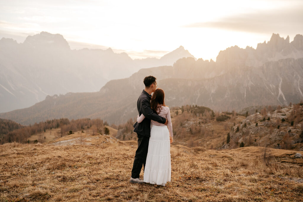 Couple embraces with mountain view at sunset.