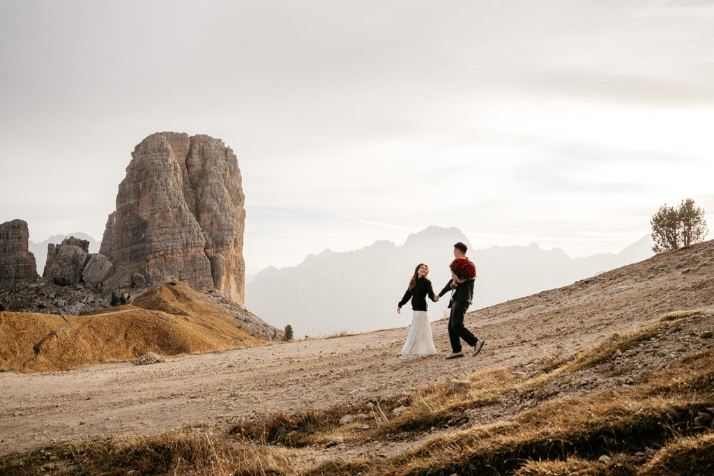 Couple walking near rock formations in mountains.