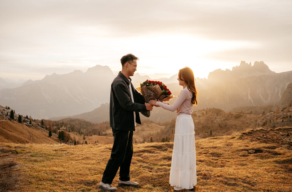 Couple exchanging flowers at sunset in the mountains.