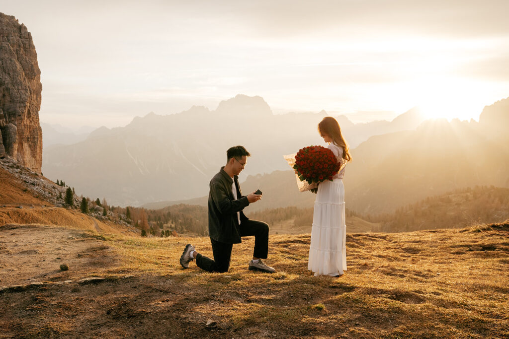 Mountain proposal at sunset, man kneeling with ring.