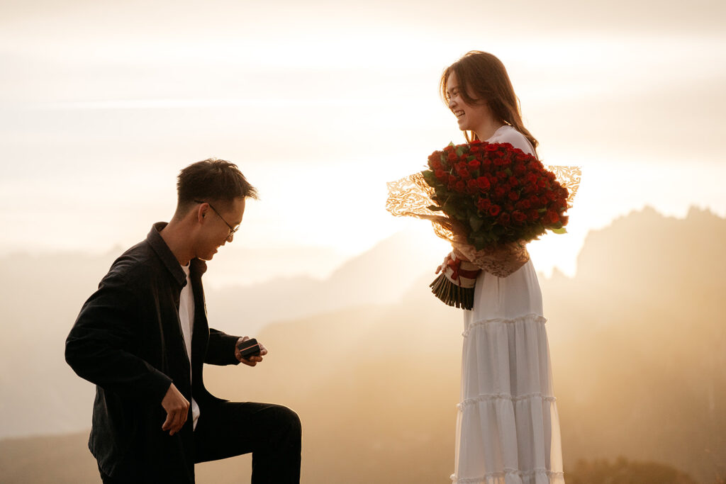 Marriage proposal at sunset with bouquet.