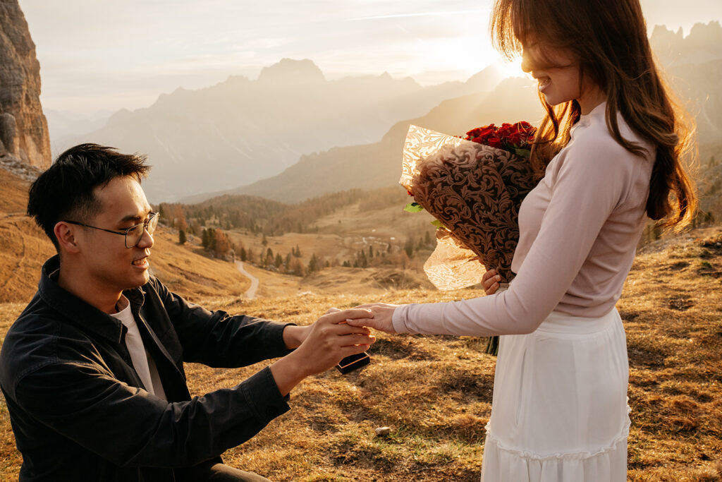 Man proposing to woman with flowers at sunset