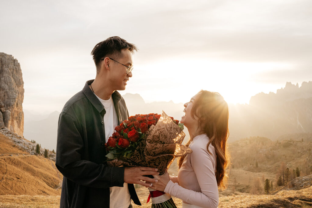 Couple smiling with roses at sunset