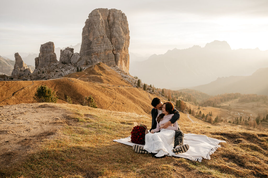 Couple embracing on mountain landscape during sunset.