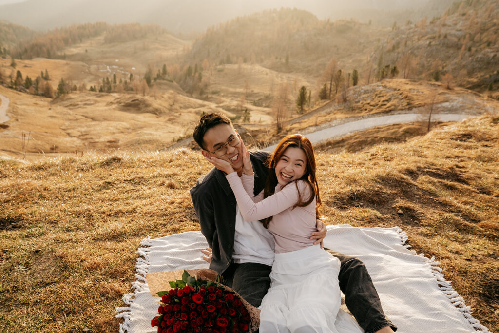 Couple smiling on picnic blanket with roses.