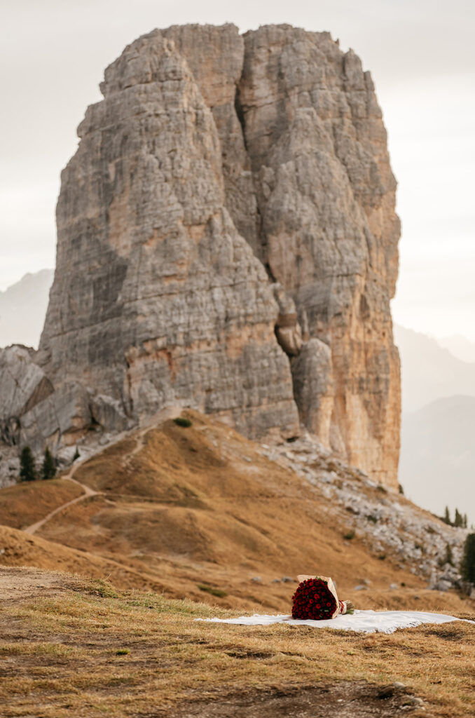 Bouquet on blanket near large rock formation.