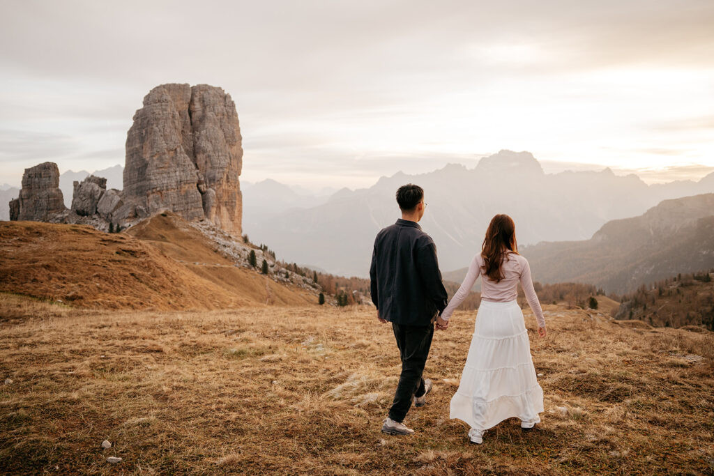 Couple walking towards mountains at sunrise.