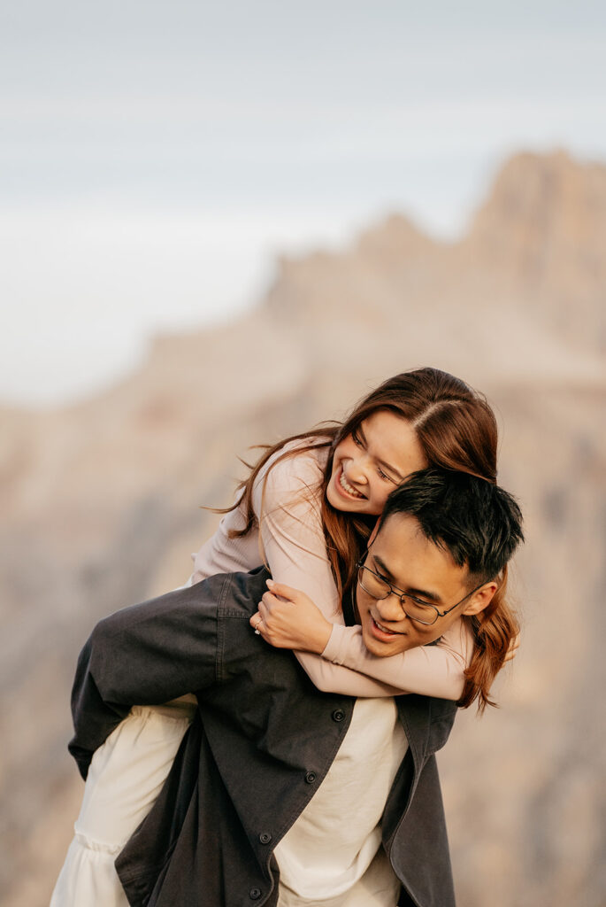 Couple smiling, piggybacking outdoors, joyful moment.