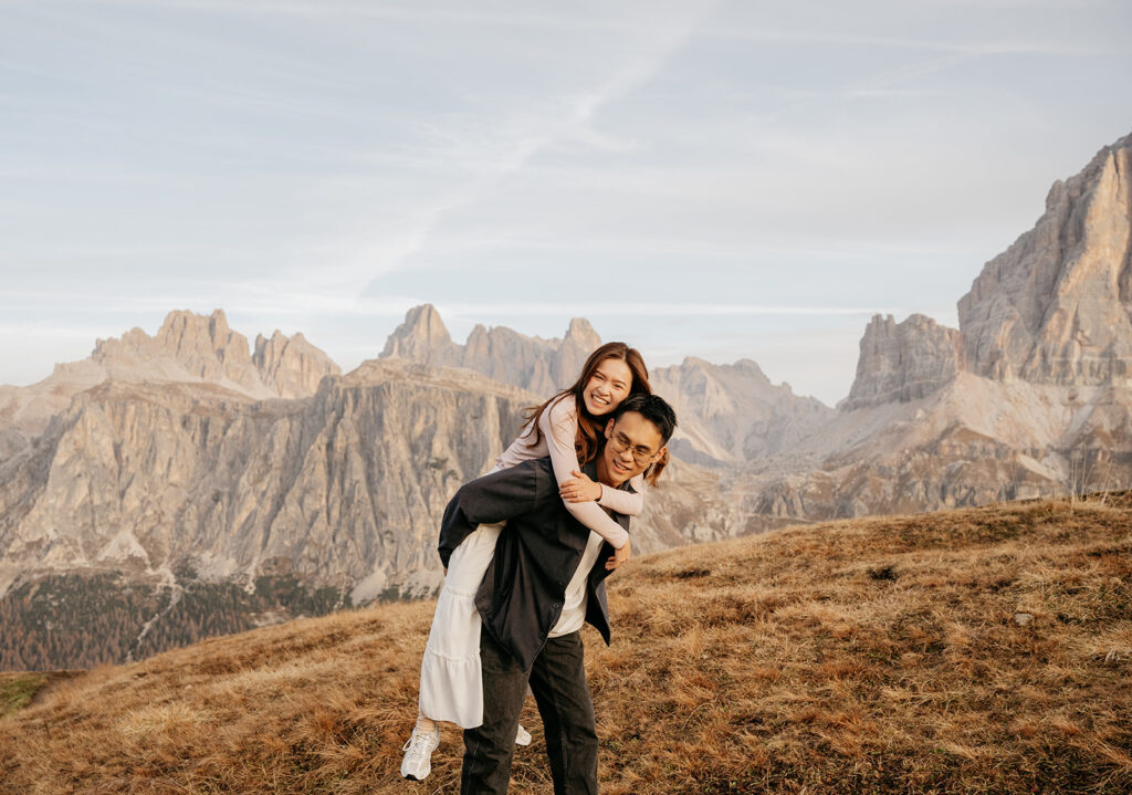 Couple piggybacking in scenic mountain landscape.