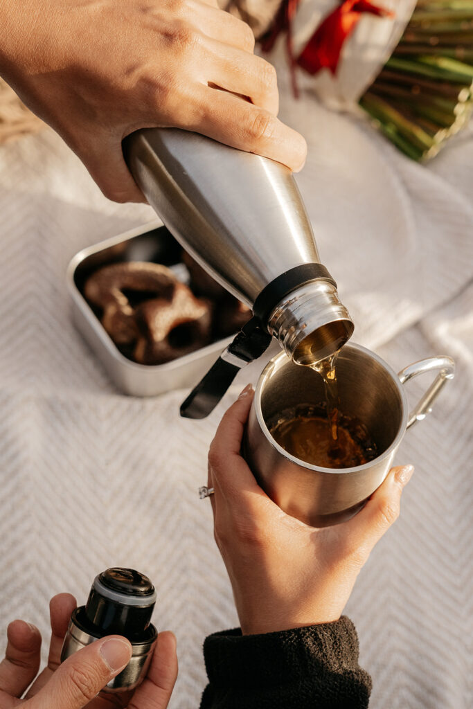 Pouring drink from thermos into cup outdoors