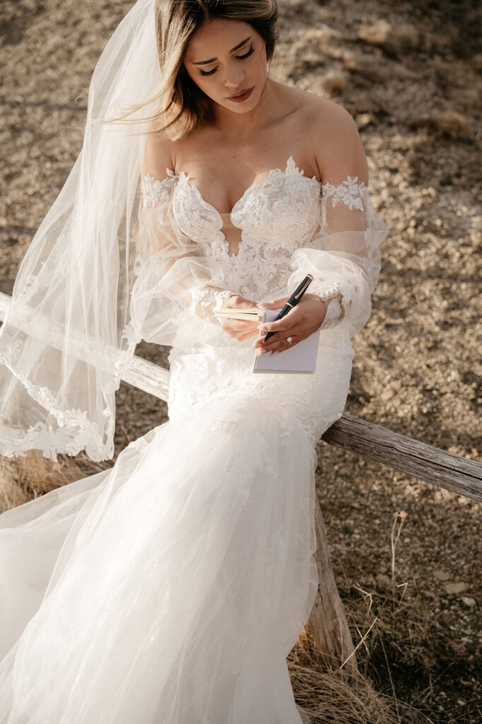 Bride in lace gown writing in a notebook