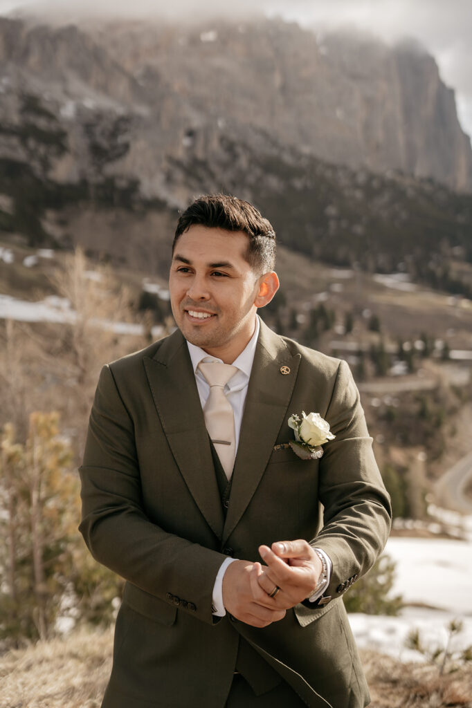 Smiling groom outdoors in green suit.