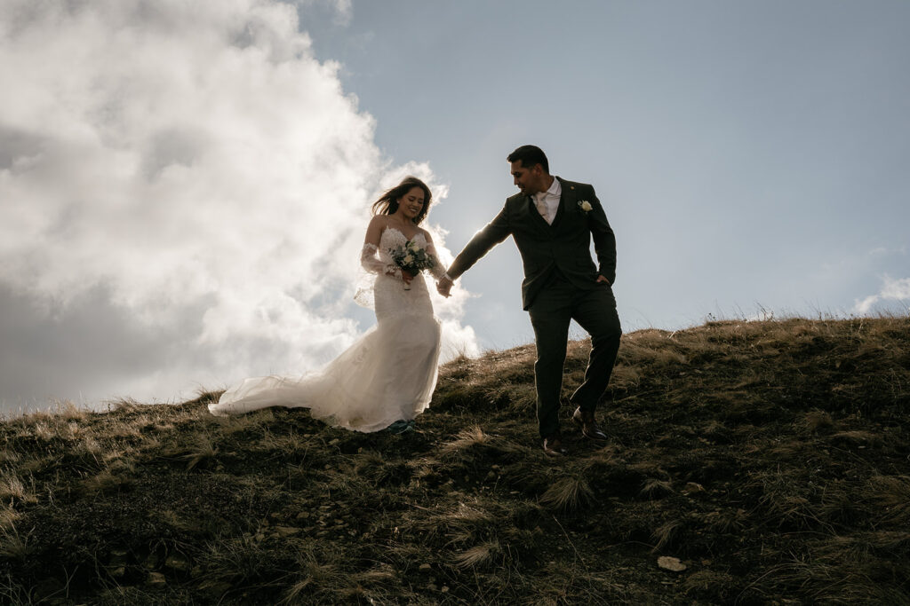 Bride and groom walking downhill on hillside