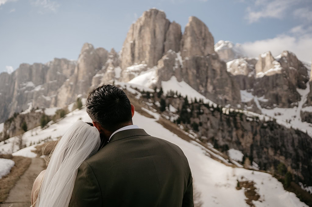 Couple embraces in snowy mountain landscape.