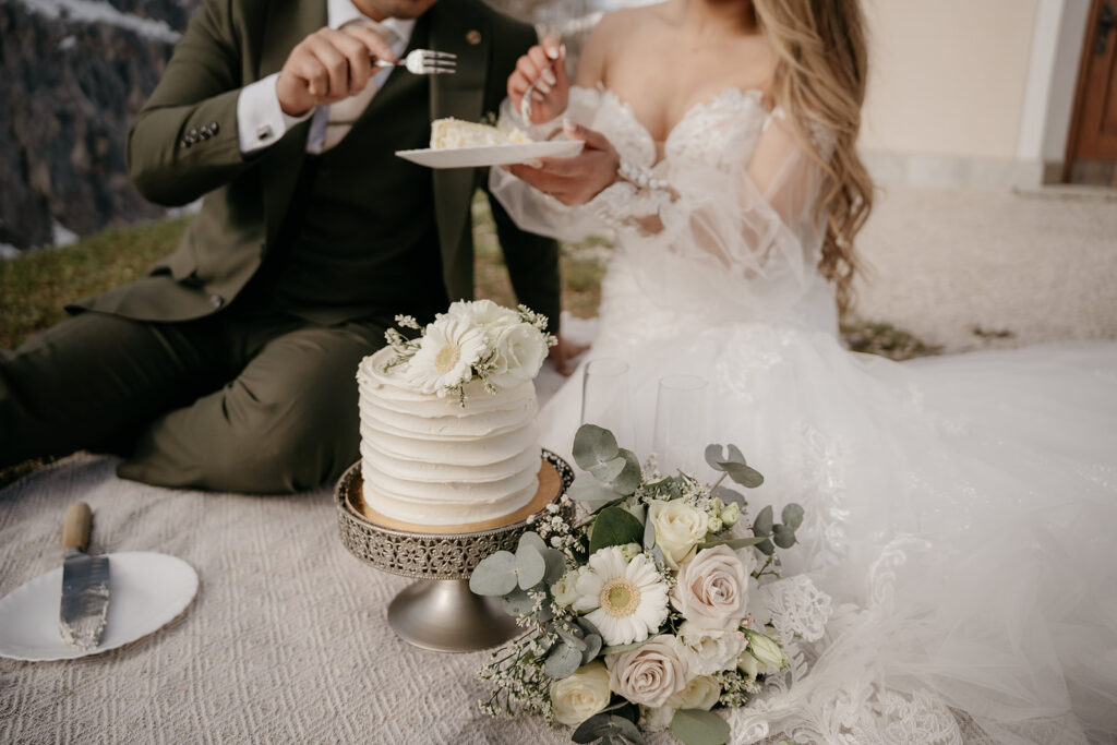 Bride and groom cutting wedding cake outdoors