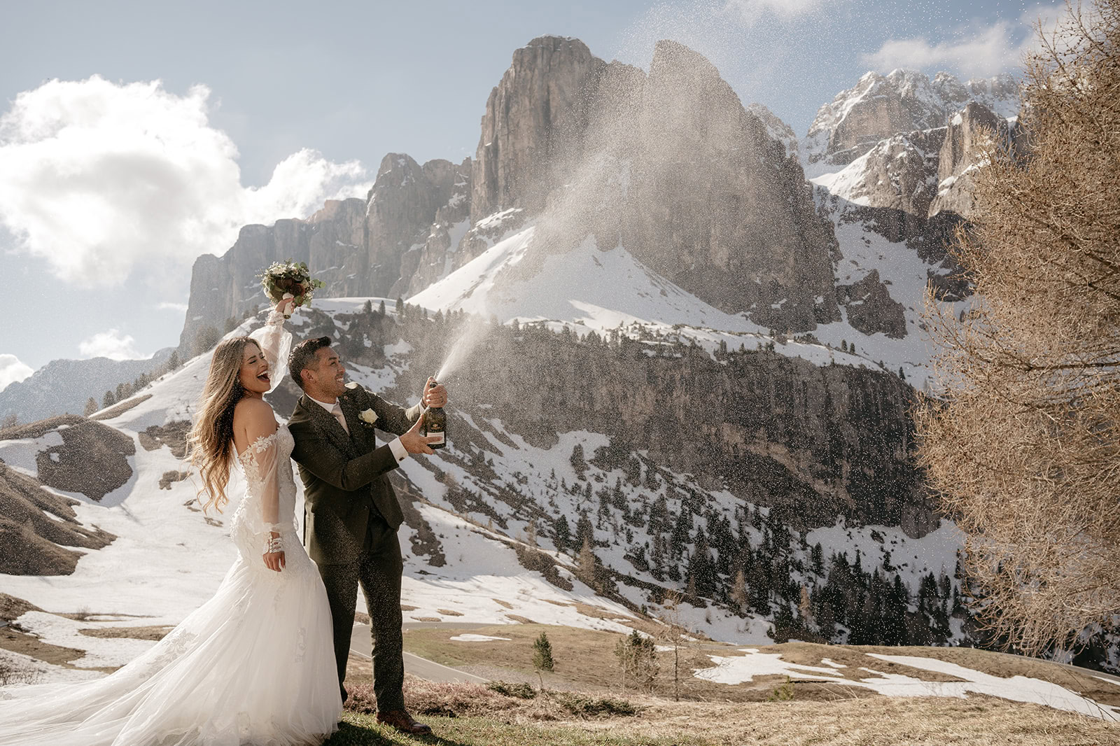 Couple celebrating with champagne in snowy mountains.