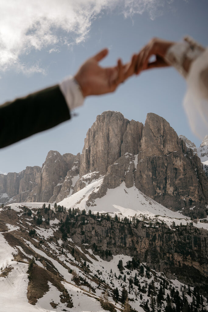 Hands holding in front of snowy mountain.