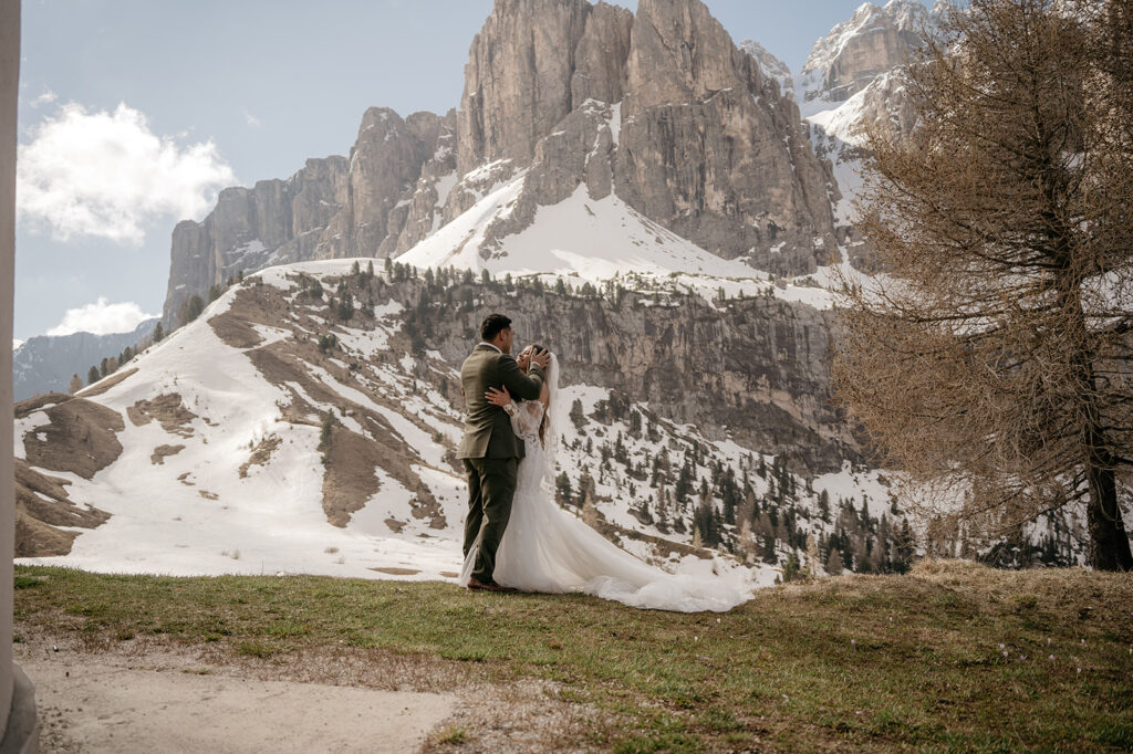 Couple embraces at snowy mountain landscape wedding.