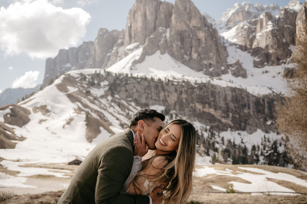 Couple embracing in snowy mountain landscape.