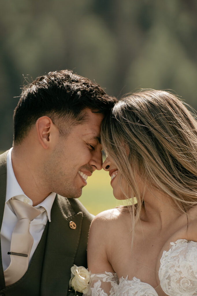 Bride and groom smiling intimately outdoors.