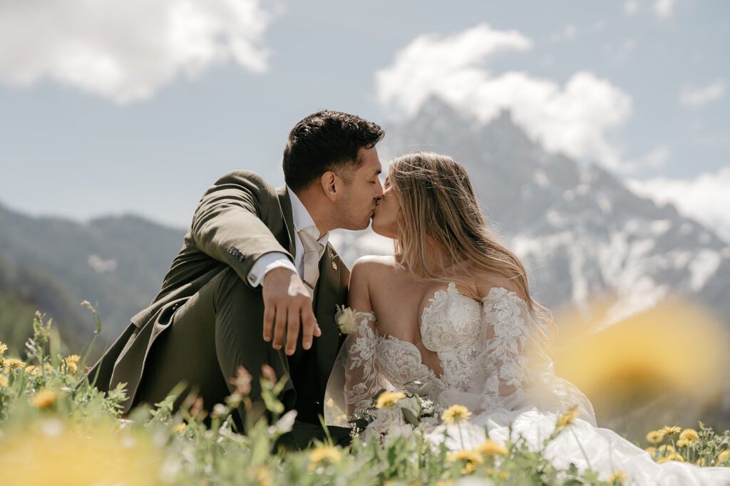 Couple kissing in mountain meadow wedding