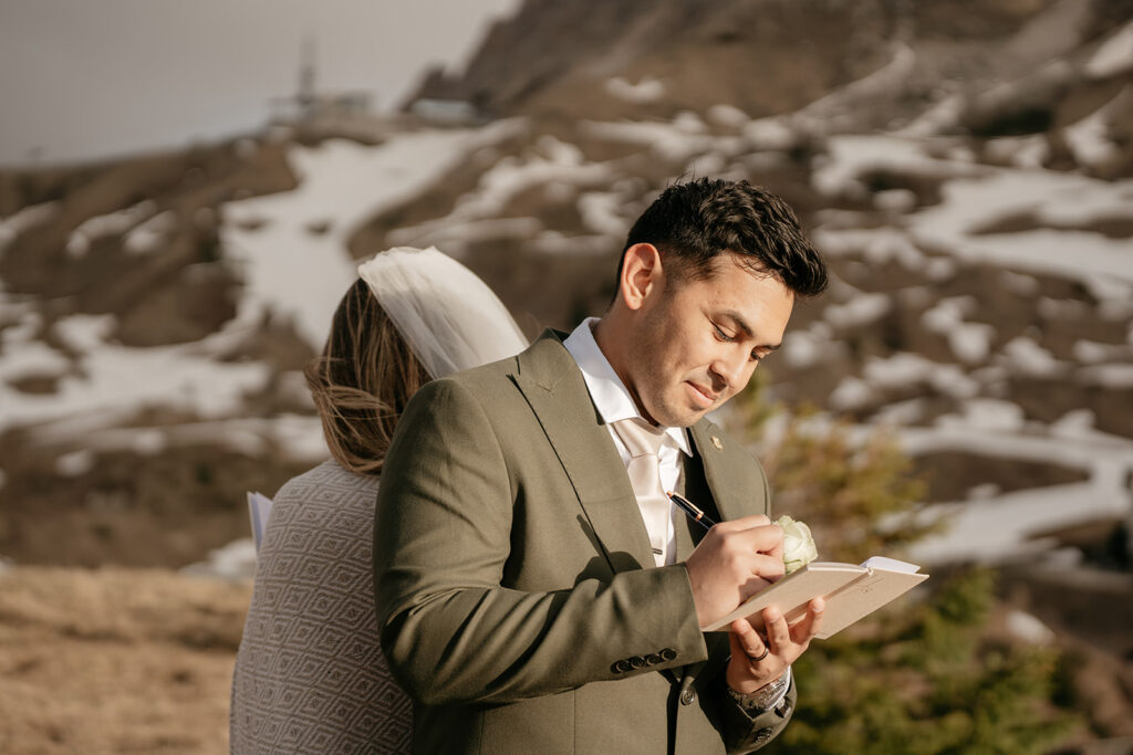 Bride and groom write vows outdoors.