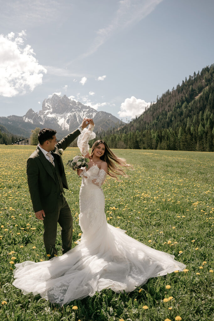 Bride and groom dancing in mountain meadow