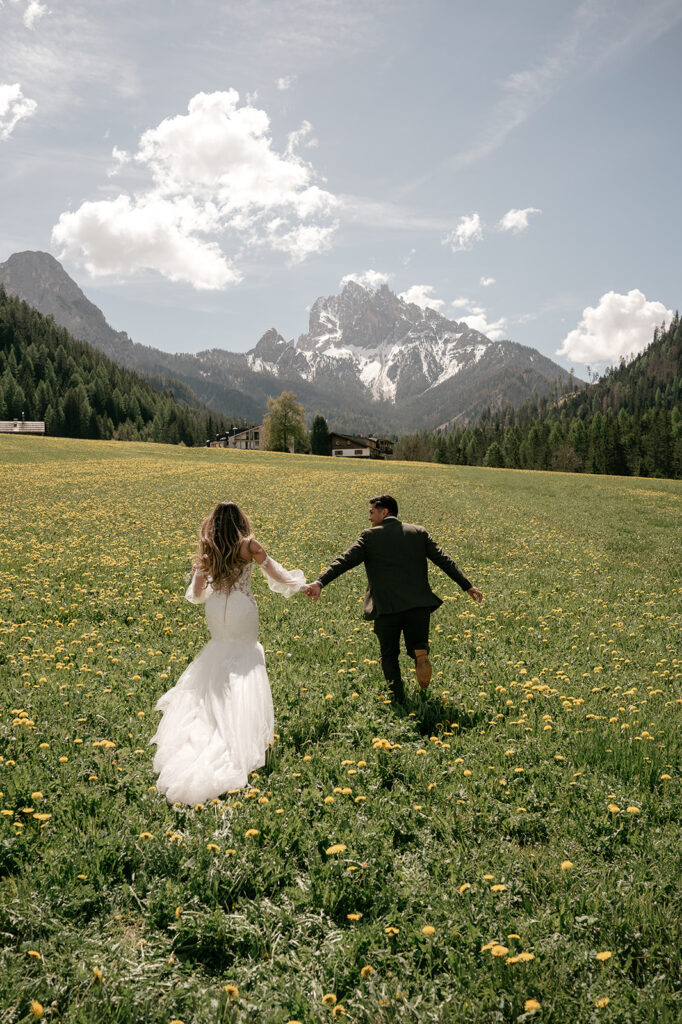 Couple running in field with mountain view