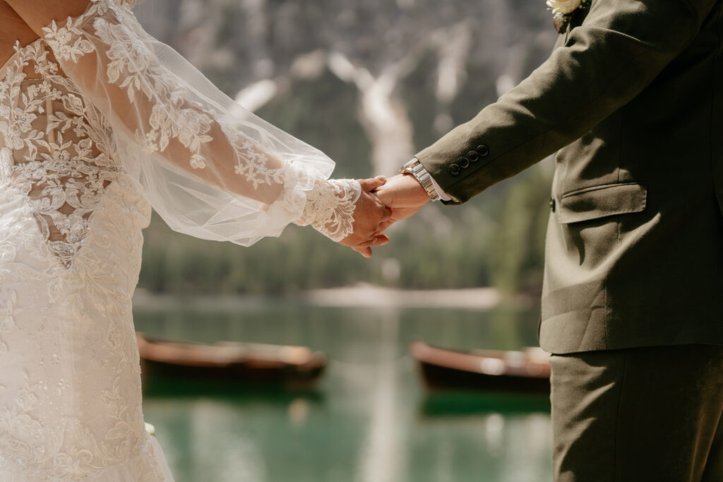 Bride and groom holding hands by lake.