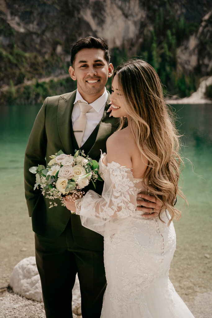 Bride and groom smiling by a lake.