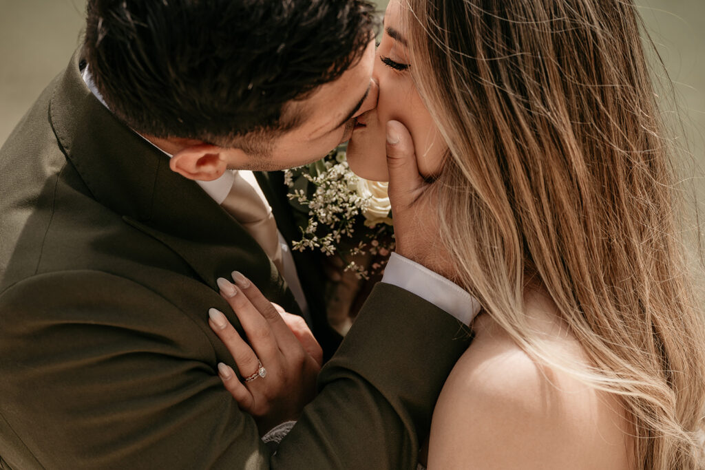 Couple kissing on wedding day with flowers.