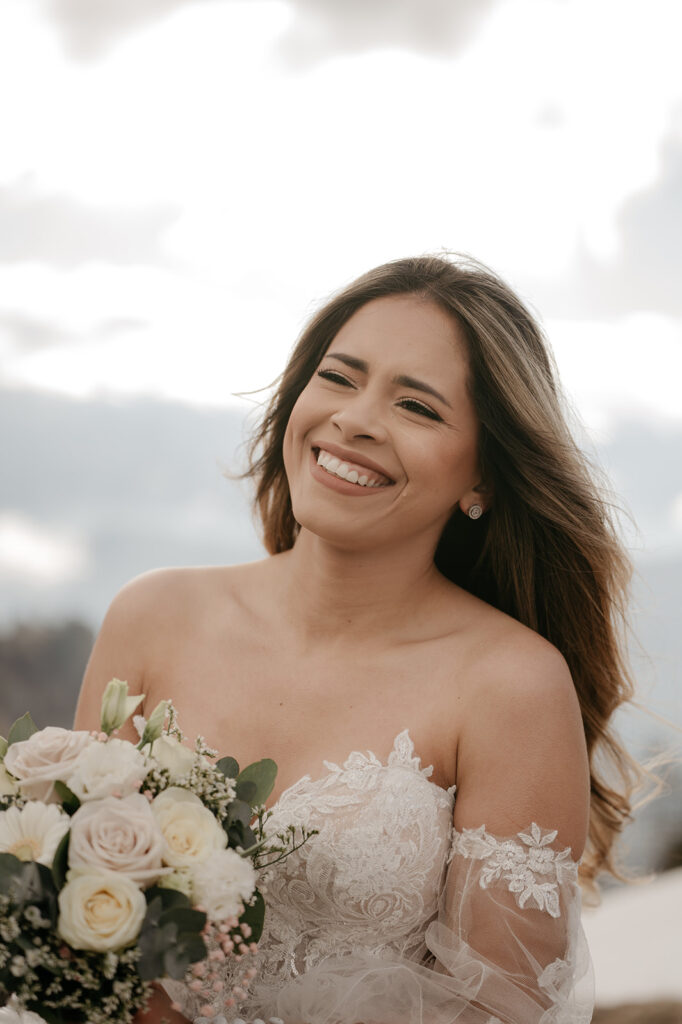 Smiling bride holding bouquet outdoors