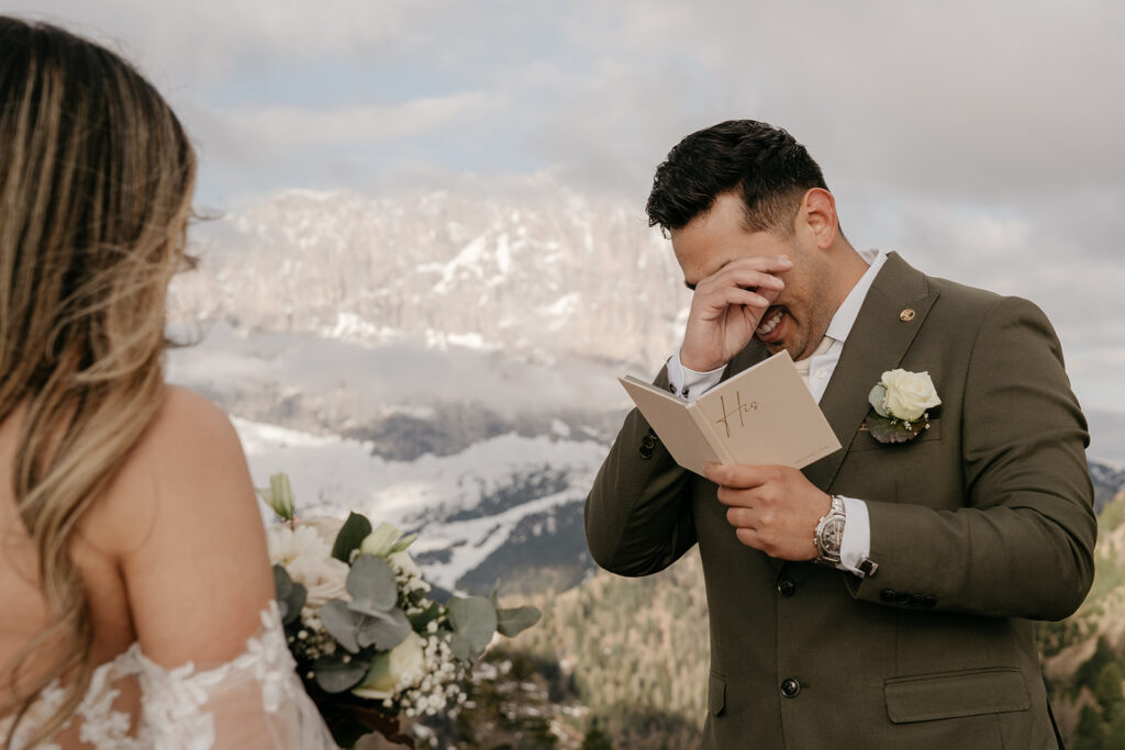 Groom reads vows, emotional mountain wedding moment.