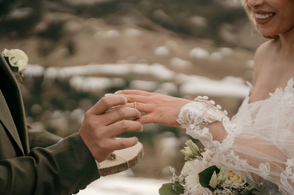 Couple exchanging wedding rings outdoors.