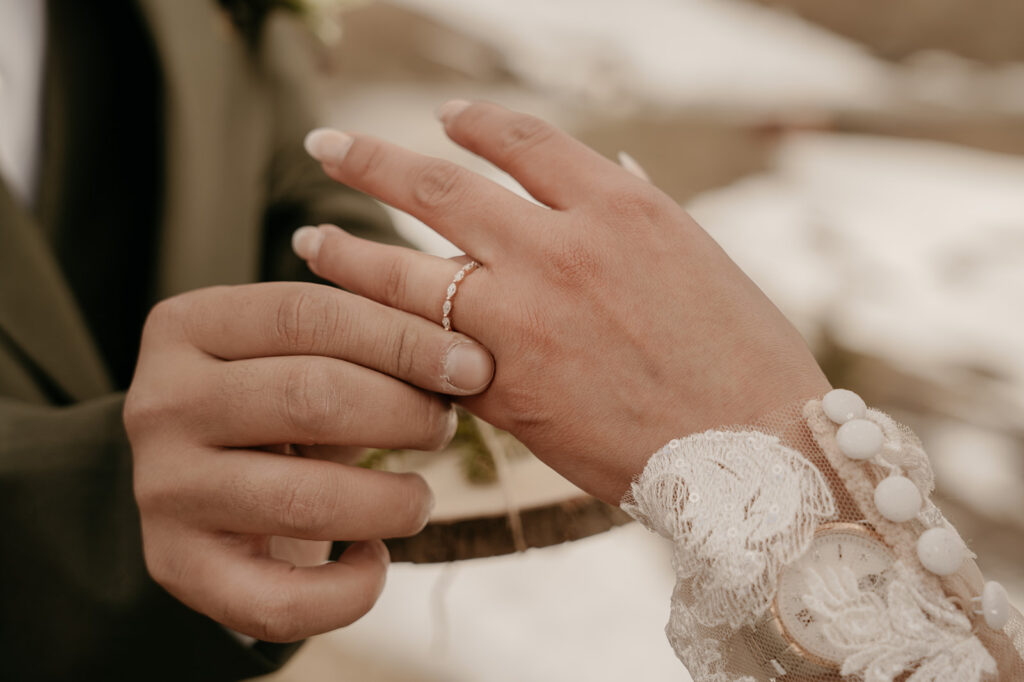 Wedding ring being placed on bride's finger.